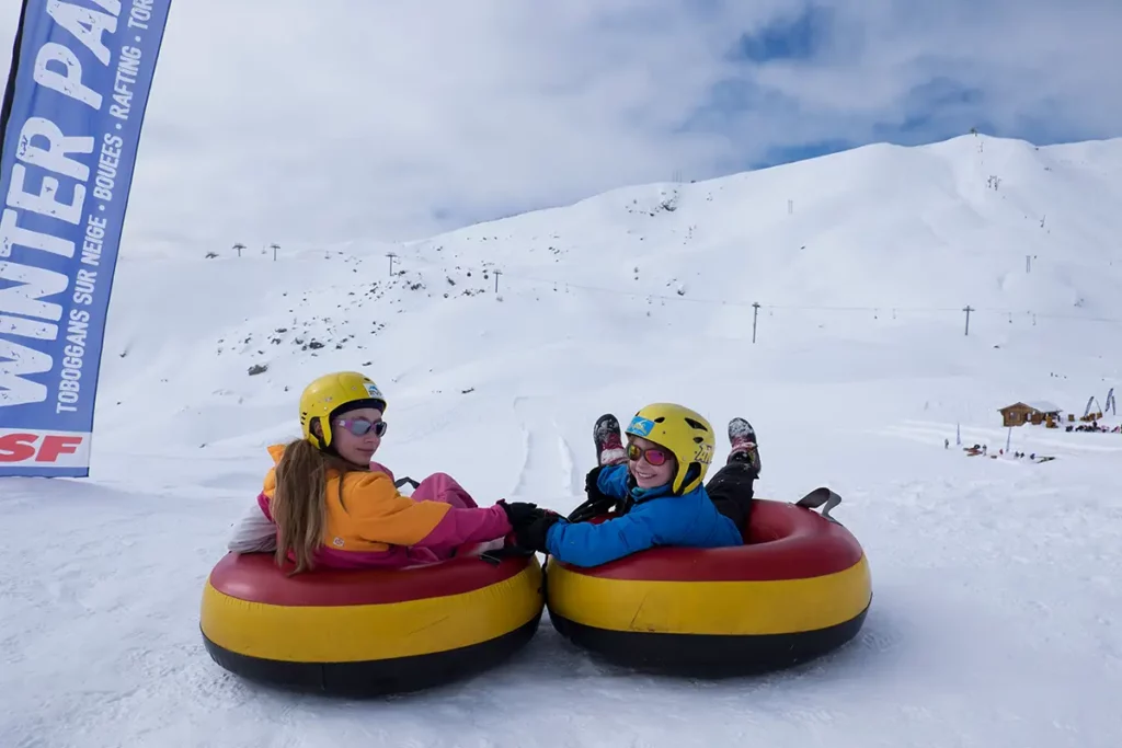 Deux enfants souriants en bouées-luge s'amusant au Winterpark d'Orcières Merlette 1850 dans les Hautes-Alpes