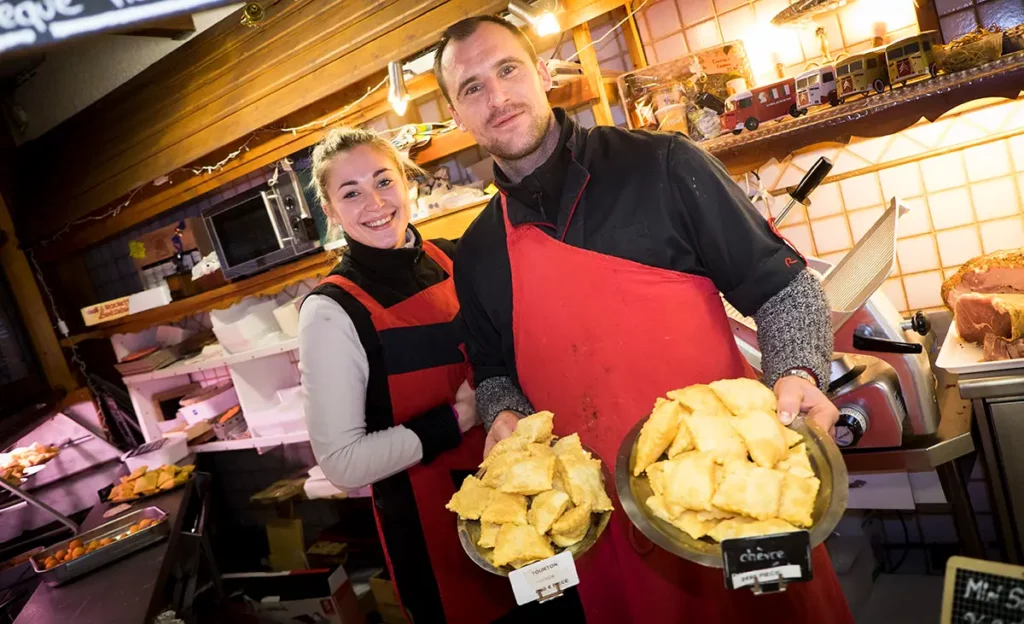 Les commerçants de la boucherie-traiteur Le Goustaron présentant des plateaux de tourtons du Champsaur à Orcières Merlette 1850 dans les Hautes-Alpes