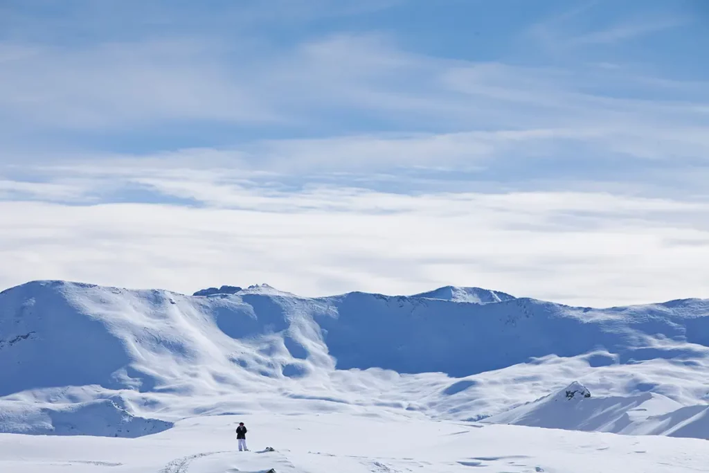 Une silhouette solitaire contemplant les immenses étendues enneigées et les sommets d'Orcières Merlette 1850 dans les Hautes-Alpes