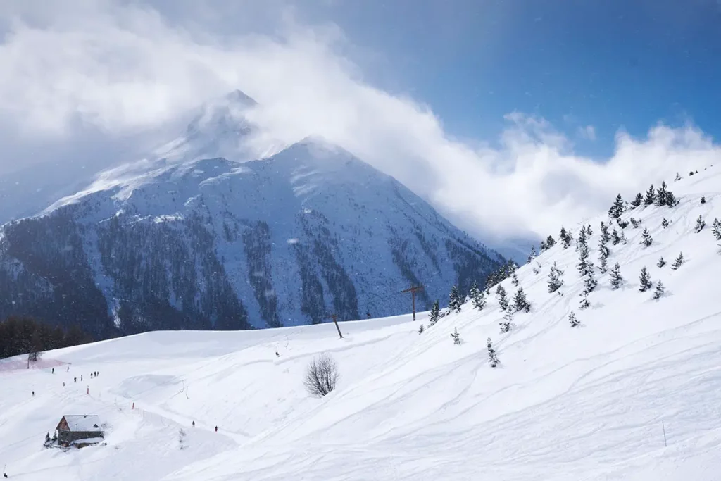 Paysage de haute montagne enneigé avec des sommets dans les nuages et des pistes à Orcières Merlette 1850 dans les Hautes-Alpes