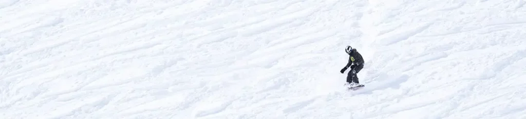 Un snowboarder en action dévalant une vaste pente enneigée à Orcières Merlette 1850 dans les Hautes-Alpes