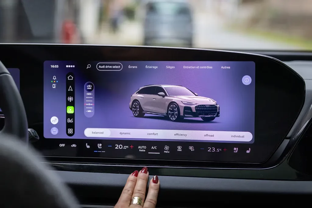 Gros plan sur l'écran central tactile de l'Audi A6 allroad e-hybrid affichant les réglages de hauteur des suspensions pneumatiques lors de mon essai automobile en Belgique