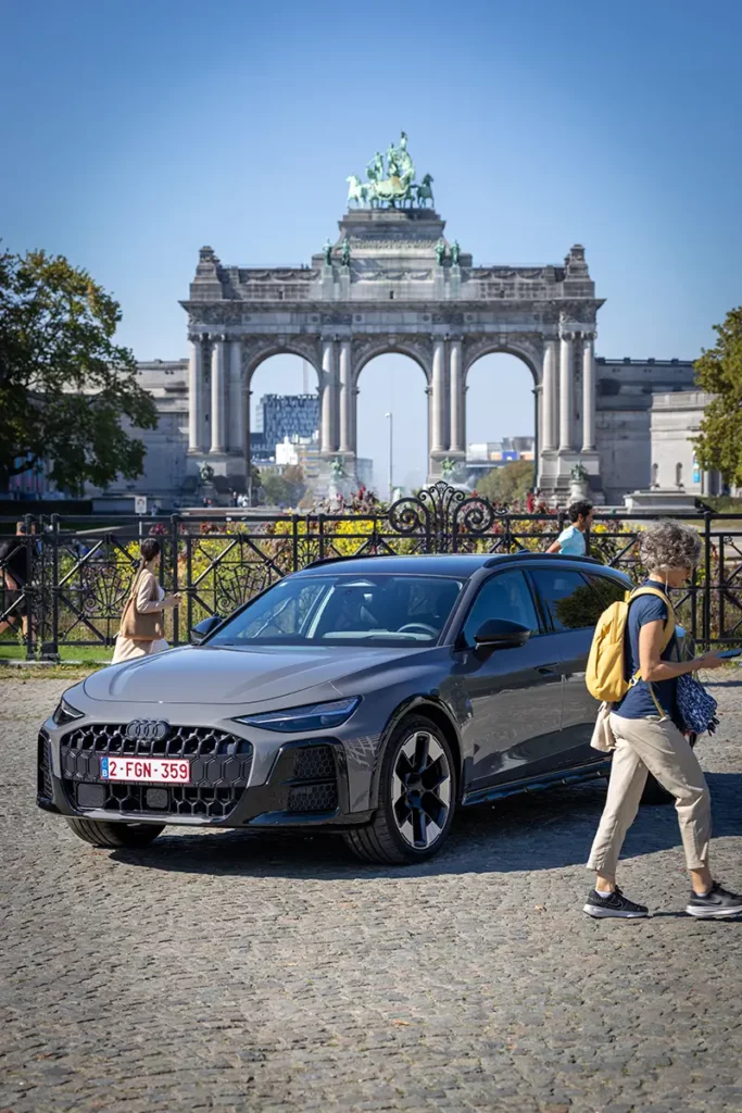 L'Audi A6 allroad e-hybrid photographiée sur fond de paysage urbain bruxellois avec des passants animant la place du Cinquantenaire