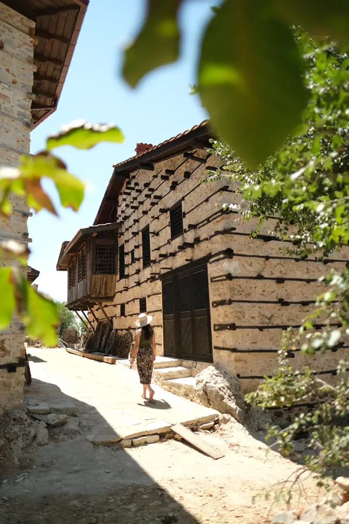 Randonneuse marchant devant les traditionnelles maisons boutons en bois et pierre du village d'Ormana avec Go Türkiye